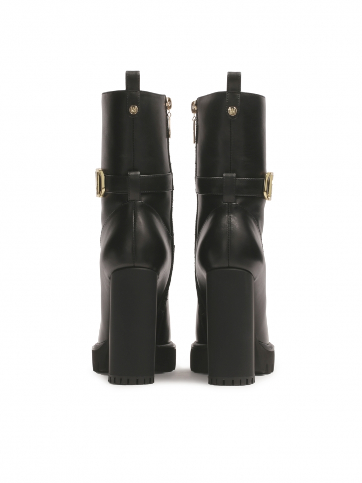 Botas KAZAR negras con monograma colocadas en un poste MORENA